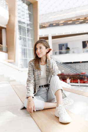 A woman is sitting in a shopping mall, laughing and smiling. Young blogger girl, close-up portrait...