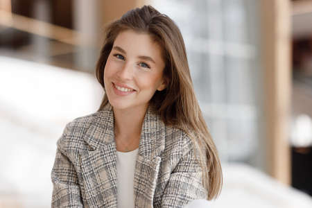 A woman is sitting in a shopping mall, laughing and smiling. Young blogger girl, close-up portrait with natural makeup.の写真素材