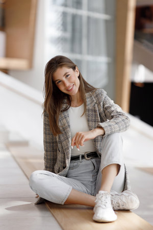 A woman is sitting in a shopping mall, laughing and smiling. Young blogger girl, close-up portrait with natural makeup.の写真素材