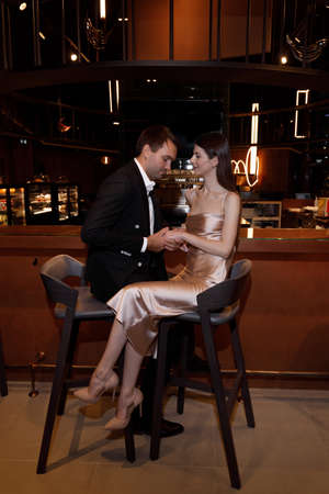 Wedding photo shoot with a lobby and restaurant, on a dark background. Beautiful young bride and groom in a stylish hotel.の写真素材