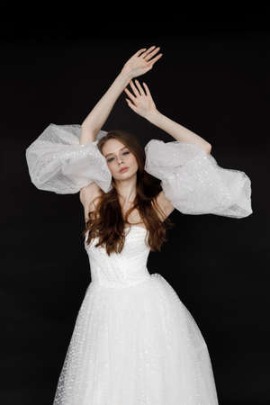 Modern stylish dress, on a black background in the studio. Portrait of a beautiful bride in a wedding dress on a dark background.の写真素材