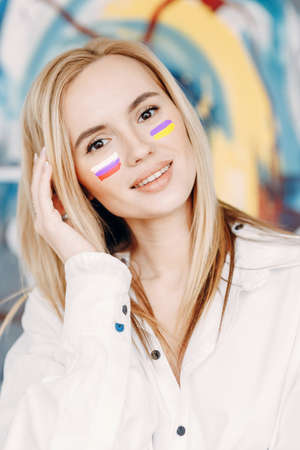 Flags are painted on the girls' faces. Twin sisters with flags of Russia and Ukraine.の写真素材