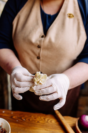 The chefs hands sculpt khinkali against the background of handmade cutting boards. Delicious homemade food, Georgian cuisine.の写真素材