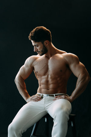 A healthy muscular young man with a bare torso, on a black background. The concept of sports and training.の写真素材