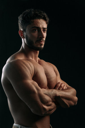 A healthy muscular young man with a bare torso, on a black background. The concept of sports and training.の写真素材