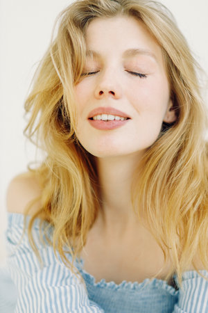 Light close-up portrait joyful girl. beautiful blonde in a blue dressの写真素材
