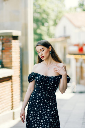 A young elegant girl posing on a city street. a beautiful business woman in a black dress on the background of the city.の写真素材