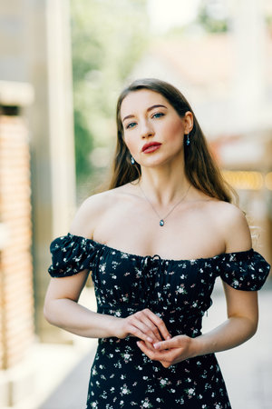 A young elegant girl posing on a city street. a beautiful business woman in a black dress on the background of the city.の写真素材