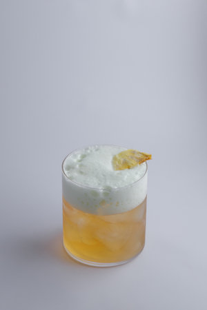 A detailed closeup view of a refreshing drink served in a stylish glass on a beautifully arranged table, showing its vibrant colors and icy elementsの写真素材