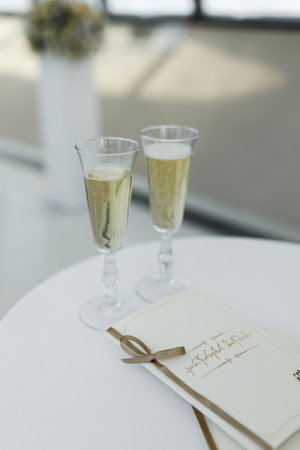 A beautifully stylish setup that showcases two elegant champagne glasses and a wedding program on a tableの写真素材