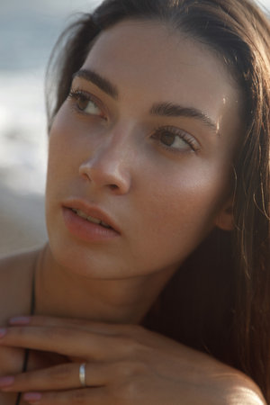 A serene and thoughtful woman gazes intently at the vast ocean, elegantly captured in soft, natural lightingの写真素材