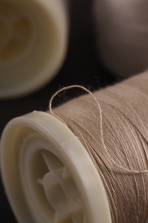 Bobbins with threads on the background of an old wooden table, sewing backgroundの写真素材