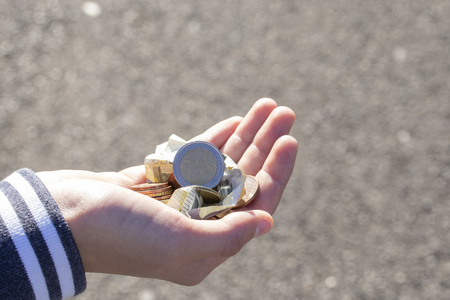 A child holds coins and euro notes in his hands. Pocket money image. Poor low-income family, the concept of poverty, beggingの写真素材