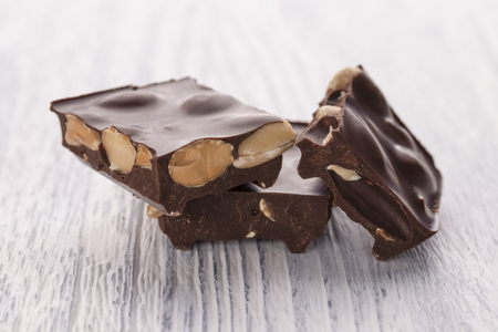 Slices of delicious dark chocolate with nuts on a white wooden table. Macro framesの写真素材