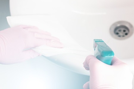 A woman washes her pink gloves with a white sink and a faucet in the bathroom at home with napkins and spray. Homework pleasureの写真素材