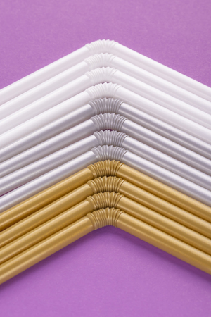 Colorful plastic drinking straws tightly pressed against each other on a purple table, close-up as...