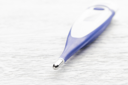 Electronic body thermometer on a white wooden background. Medical instrumentの写真素材