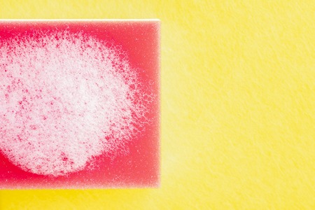Red-white sponge for washing with foam on yellow matte. Free space for inscriptions and designの写真素材