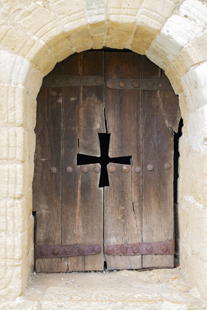 The window of the Catholic Church in the form of an arch with wooden shutters and carved cross. Concept of faith in Godの写真素材