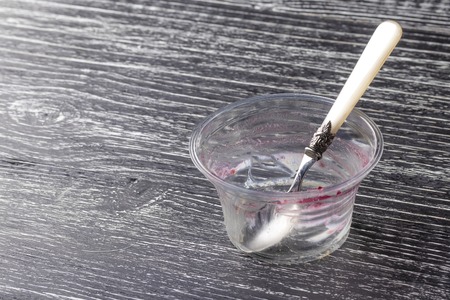empty plastic packaging with a spoon, leftovers eaten by teramis on a dark wooden backgroundの写真素材