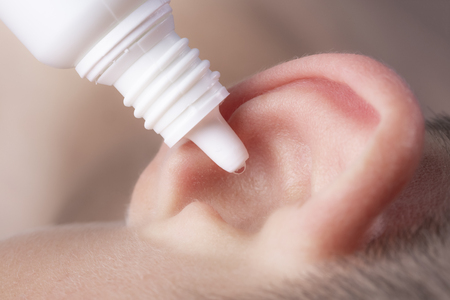 Medical pipette with a drop of medication over the patient's ear. Ear diseasesの写真素材