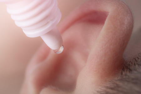 Medical pipette with a drop of medication over the patient's ear. Ear diseasesの写真素材
