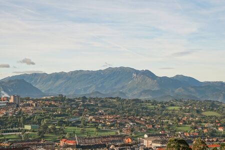 A beautiful European city at the foot of a mountain against a blue sky. The concept of living in a quiet town near wildlifeの写真素材