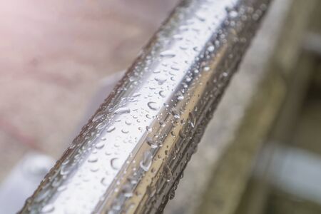 Drops of water on a chrome-plated shiny railing after rain on a concrete structure background. Autumn conceptの写真素材