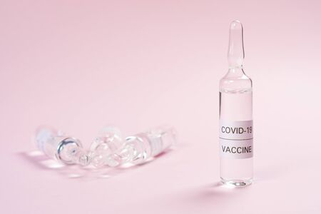 Coronavirus vaccine. Glass ampoules with a medicine for COVID-19 on a pink background. Copyspace. Close-up. Search and application of a new injectionの写真素材