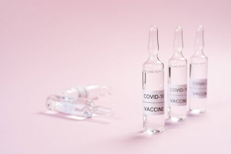 Coronavirus vaccine ampoules on a pink background. Copyspace. Close-up. Development and application...
