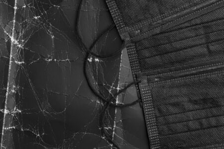 Black medical masks on black crumpled paper with wrinkles and folds. Abstract dark dramatic background. Disposable protective surgical masks. Copyspace. Coronavirus Preventionの写真素材