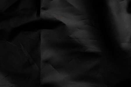 Wrapping black material with wrinkles and wrinkled folds. Old crumpled synthetic fabric. Abstract dramatic background. For design and headlines.の写真素材