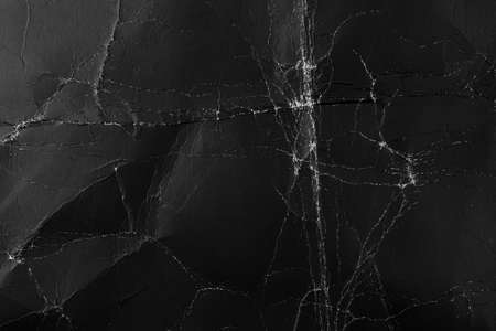 Worn black cardboard with wrinkles and scuffs. Paper dark abstract background for design. Packaging material. The concept of Halloween and horror moviesの写真素材