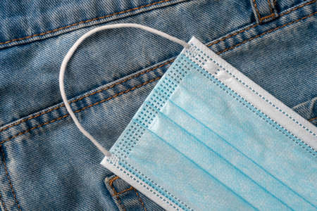 Medical protective surgical mask in a pocket of blue jeans close-up. Coronavirus protection conceptの写真素材