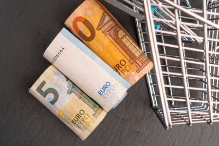 Rolled euro money in a supermarket shopping cart on a dark background. Online shopping concept.の写真素材