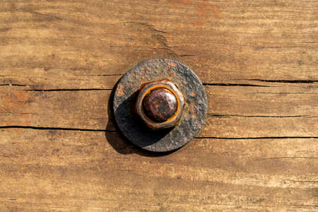 Rusty corroded nut with washer on a threaded bolt on an old cracked worn wooden board. Close up. Copy spaceの写真素材