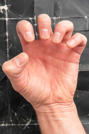 Man clenching fist on black grunge background close up