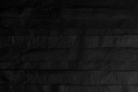Black crumpled synthetic stripes. Wrinkled horizontal layers. Abstract dark backgroundの写真素材