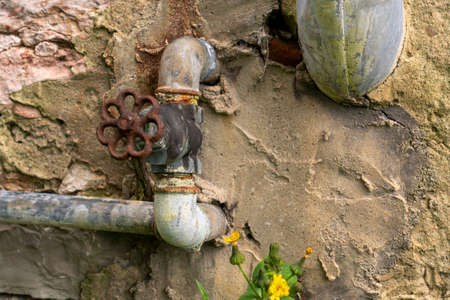 Old abandoned valve with pipe on a stone wall close upの写真素材
