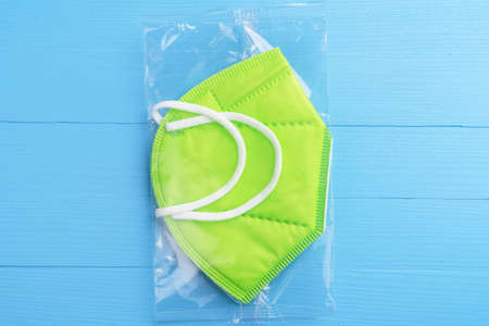 Respiratory color green medical mask on plank background. Plastic new pack. Close-up. KN95