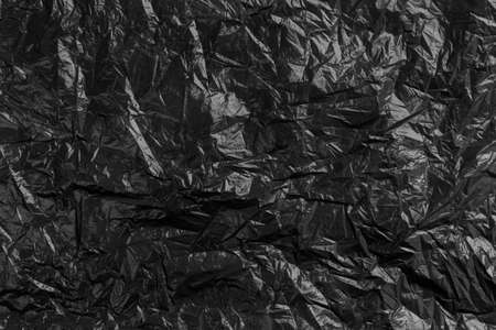 Plastic black crumpled disposable trash bag. Abstract recycled backgroundの写真素材