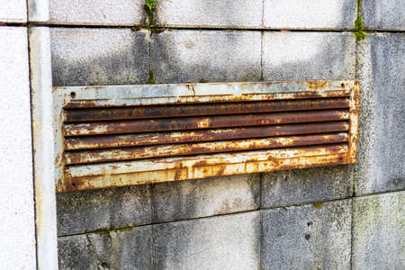 Old rusty shabby ventilation grill on a mossy tiled wall. Close-up. Abstract viewの写真素材