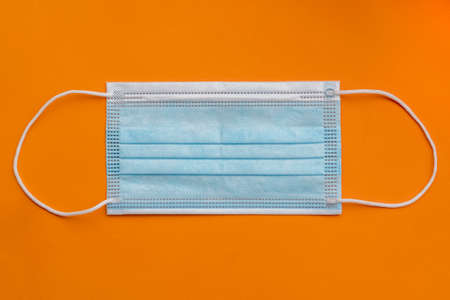 One medical surgical protective face mask close up on orange colorful background