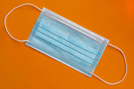 New medical protective surgical mask on a bright orange background. Close-up