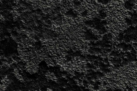 Old black wall with peeled weathered dark paint. Abstract textured background