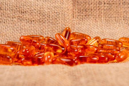 Fish salmon oil capsules on a rough rustic burlap. Closeup. Natural supplement Omega 3