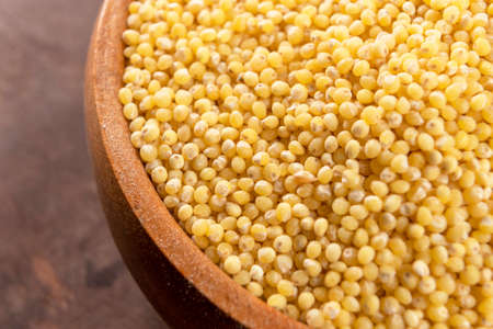 Full rustic wooden bowl with dry millet on a wooden table. Macro. Selective focusの写真素材