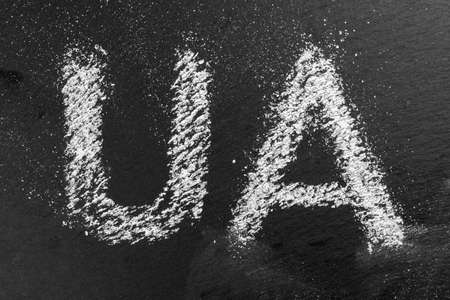 Grunge lettering UA, symbolizing Ukraine and the war with Russia. Letters written in chalk on a chalkboard close-up. The concept of military aggression against an independent countryの写真素材