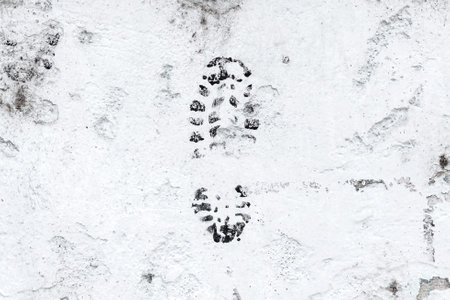 A single dirty grungy boot print on a white cement wall close-up. abstract view.の写真素材