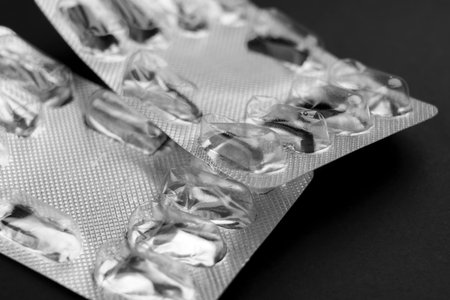 Empty used pharmaceutical medical blister pill packs without capsules on black backgroundの写真素材
